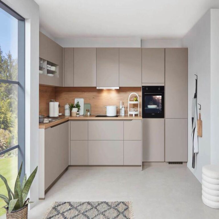 Musterküche in Kaschmir als L-Küche mit Holzrückwand und Backofen im Hochschrank – Küchenstudio Heilbronn